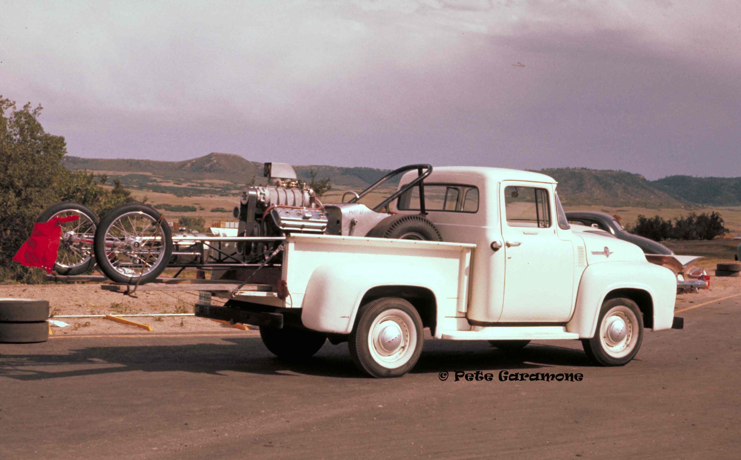 A picture of a white truck carrying a vintage motor