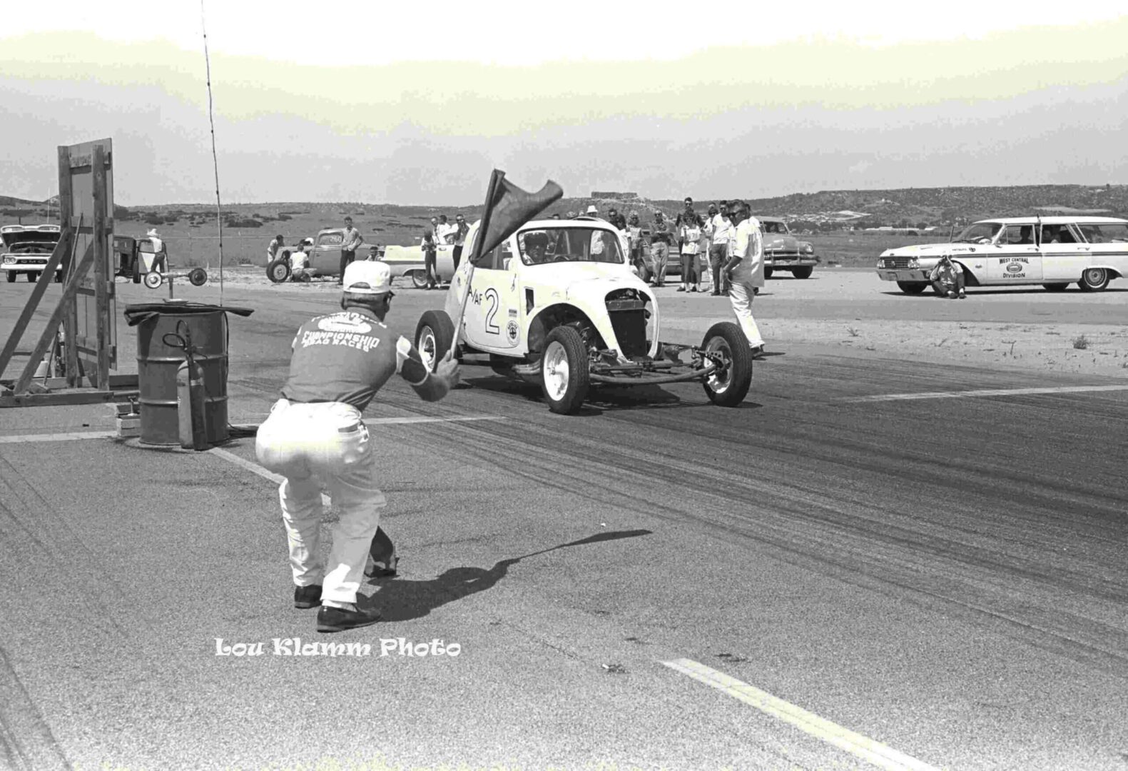 A picture of a man with a flag at a car event