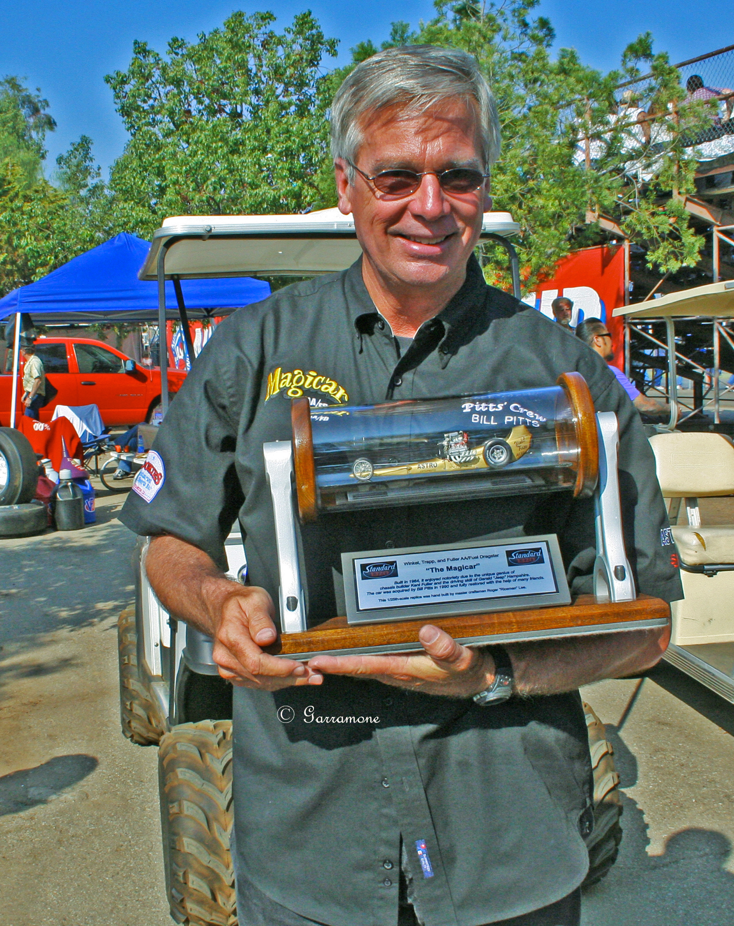 A picture of an man holding an award of a motor event